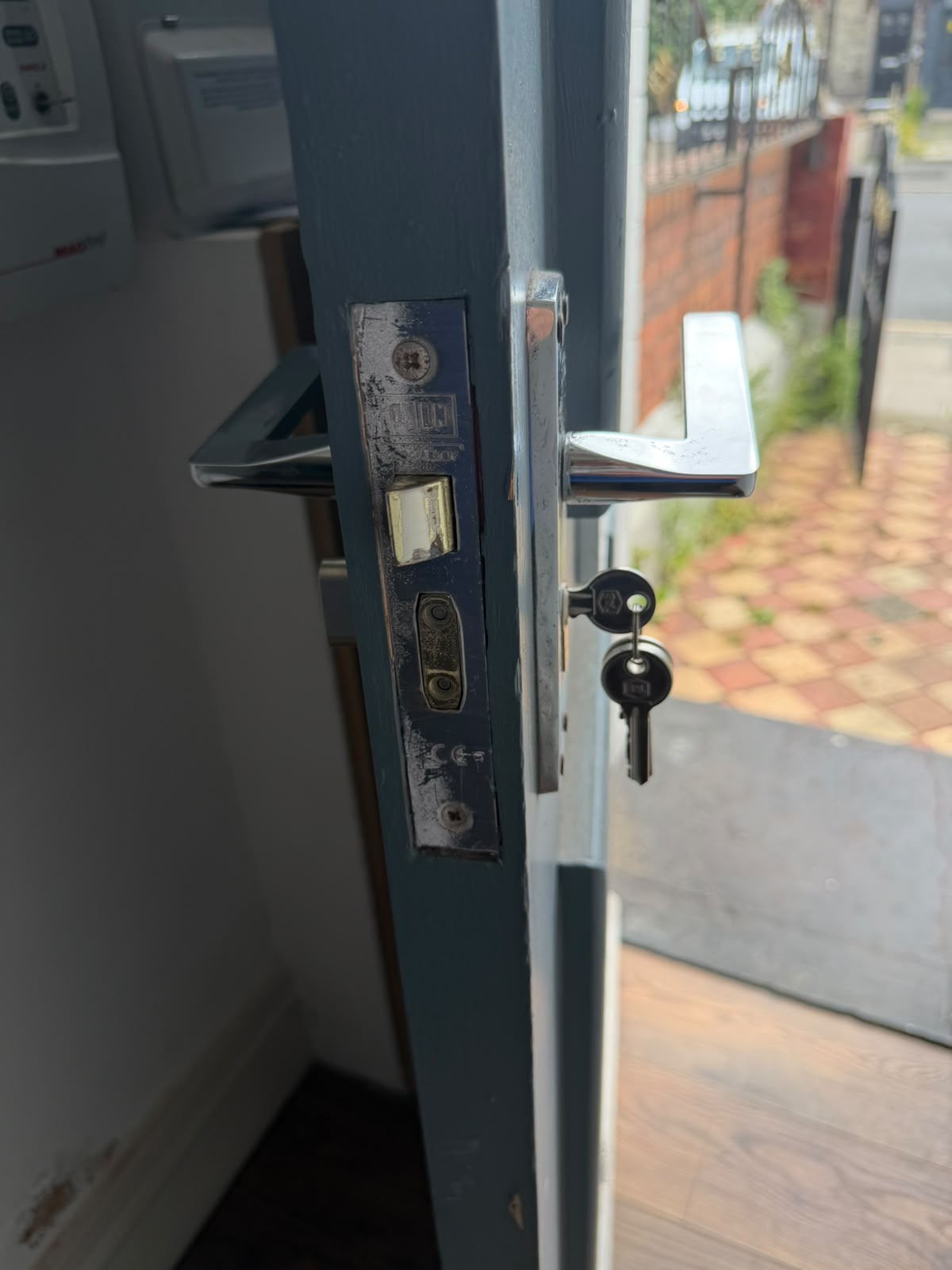 Correctly sized replacement euro-cylinder and new keys fitted into the mortice lock of a grey painted front door