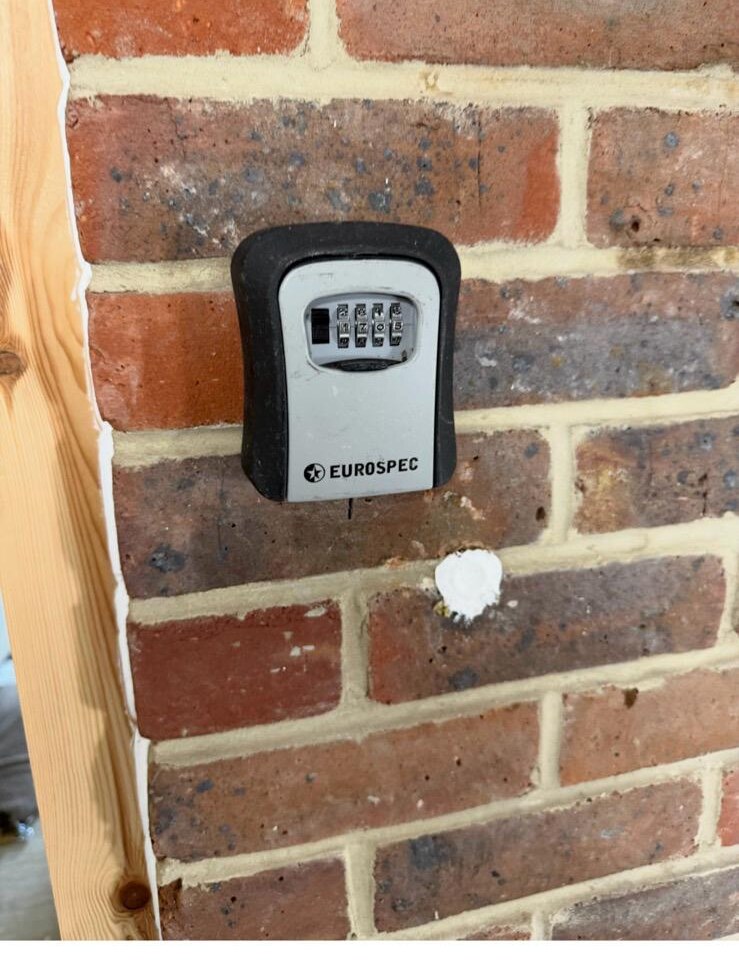 Eurospec combination key safe fitted to a brick wall next to a housing association front door, with new keys inside